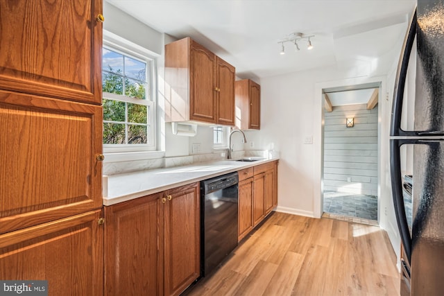 kitchen with light countertops, brown cabinets, light wood-style floors, black appliances, and a sink