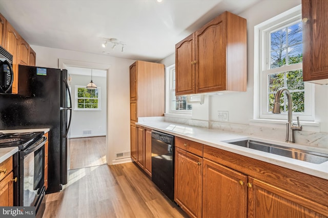 kitchen featuring a sink, plenty of natural light, black appliances, and light wood finished floors