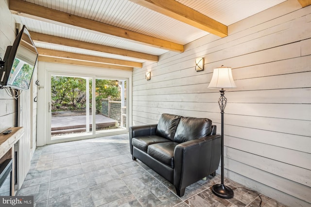 sitting room featuring beamed ceiling and wooden walls