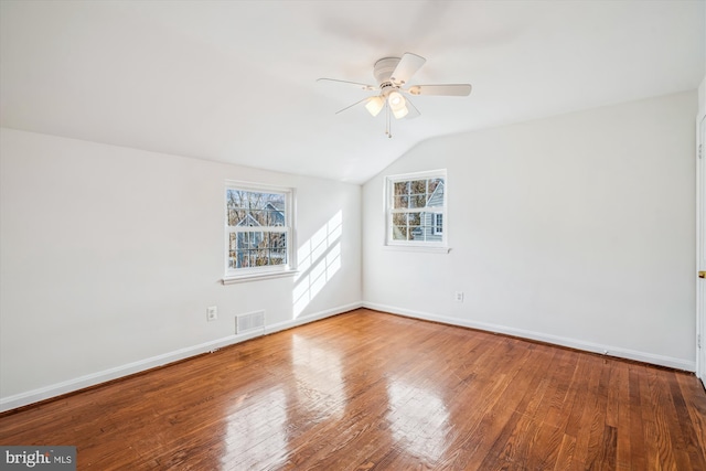 unfurnished room featuring visible vents, baseboards, lofted ceiling, hardwood / wood-style flooring, and a ceiling fan