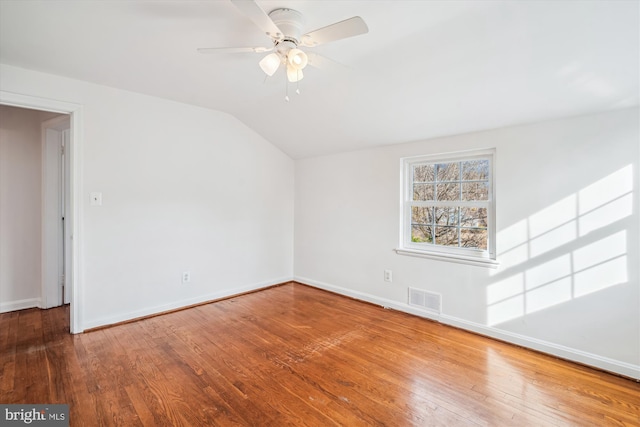 spare room with vaulted ceiling, hardwood / wood-style flooring, baseboards, and visible vents