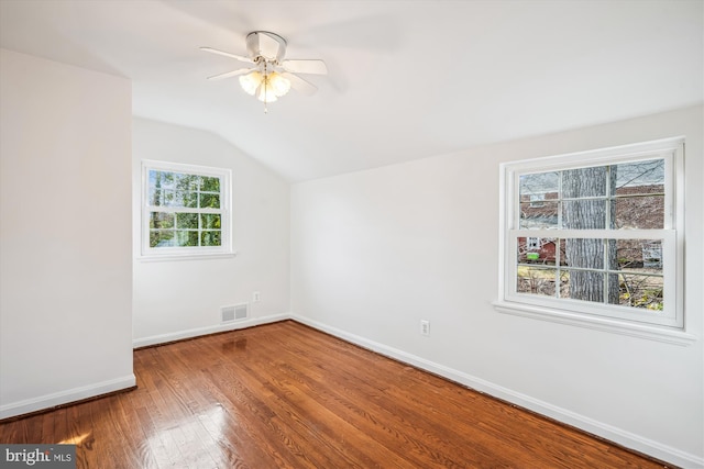 spare room with visible vents, lofted ceiling, hardwood / wood-style flooring, baseboards, and ceiling fan