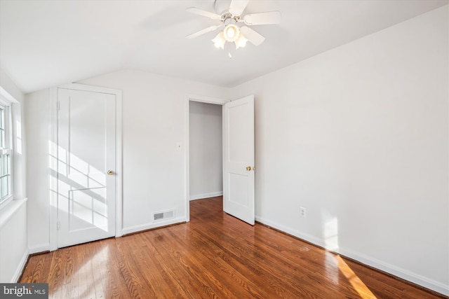 unfurnished bedroom with vaulted ceiling, visible vents, baseboards, and wood finished floors