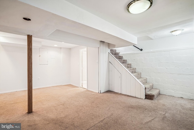 finished basement featuring baseboards, stairway, light carpet, electric panel, and concrete block wall