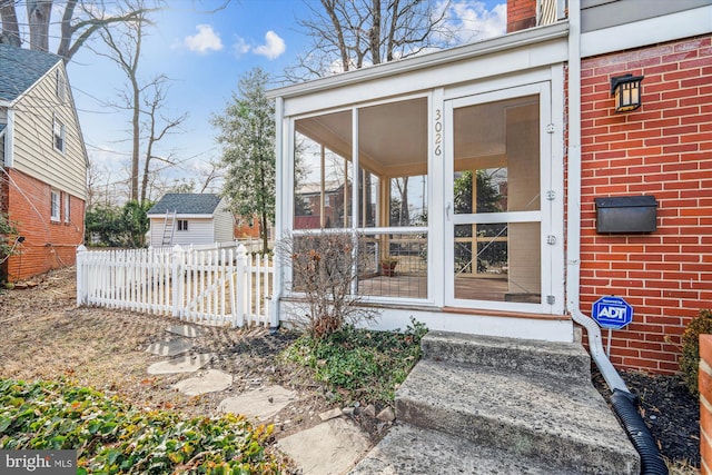 property entrance with brick siding, a chimney, and fence