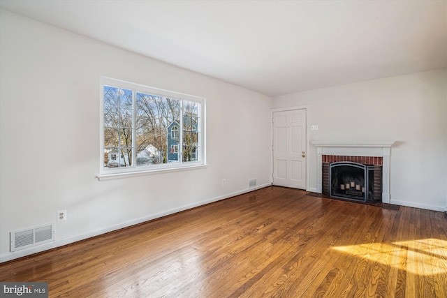 unfurnished living room featuring visible vents, a fireplace, baseboards, and wood finished floors