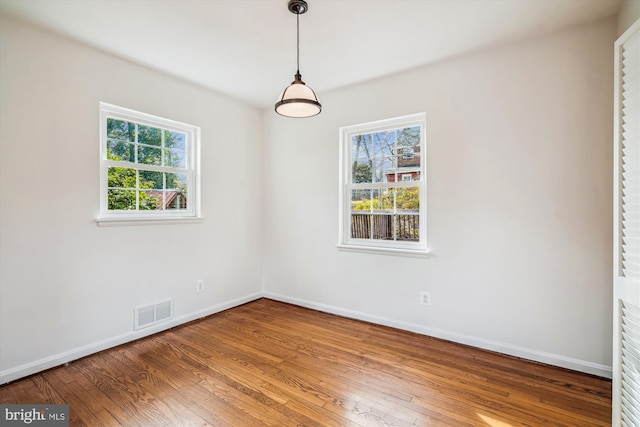 empty room with visible vents, baseboards, and hardwood / wood-style floors