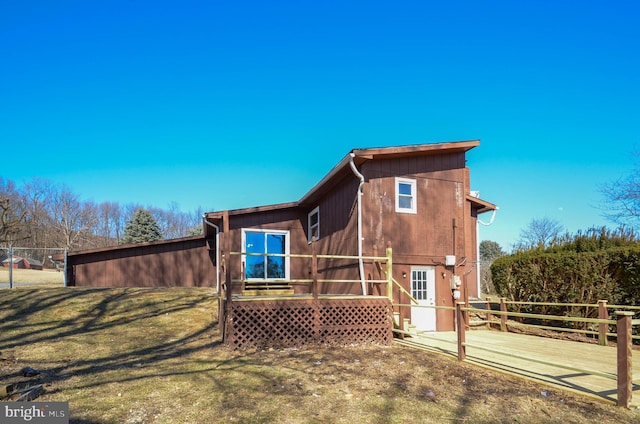 back of house featuring a deck, a lawn, and fence