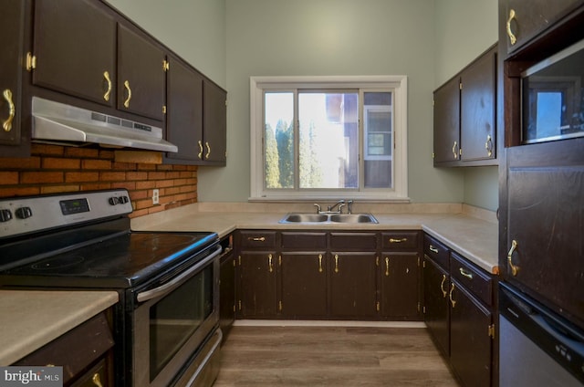 kitchen featuring under cabinet range hood, stainless steel appliances, wood finished floors, a sink, and light countertops