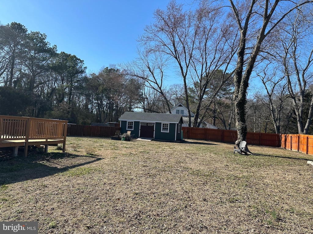 view of yard with an outdoor structure, a fenced backyard, and a wooden deck