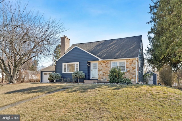 view of front facade featuring a front lawn, stone siding, a detached garage, roof with shingles, and a chimney