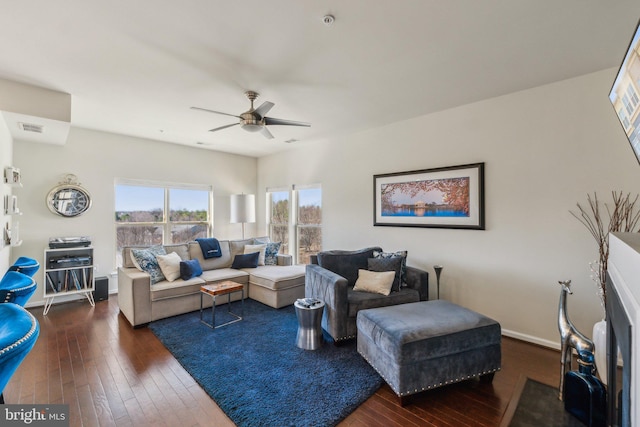 living area with visible vents, baseboards, dark wood-type flooring, and ceiling fan