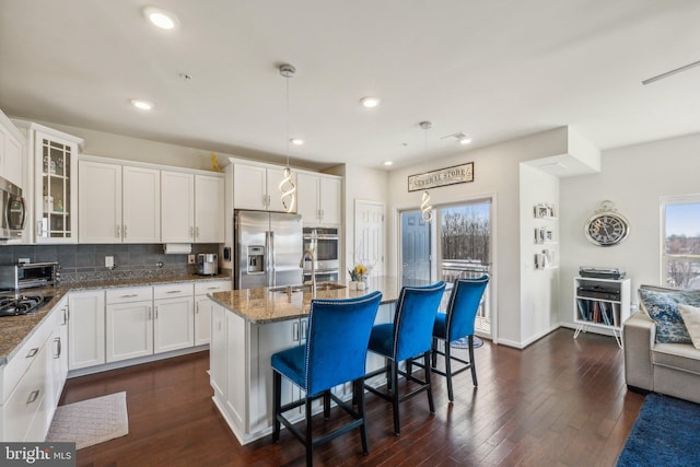 kitchen featuring dark wood finished floors, stone countertops, appliances with stainless steel finishes, white cabinetry, and tasteful backsplash