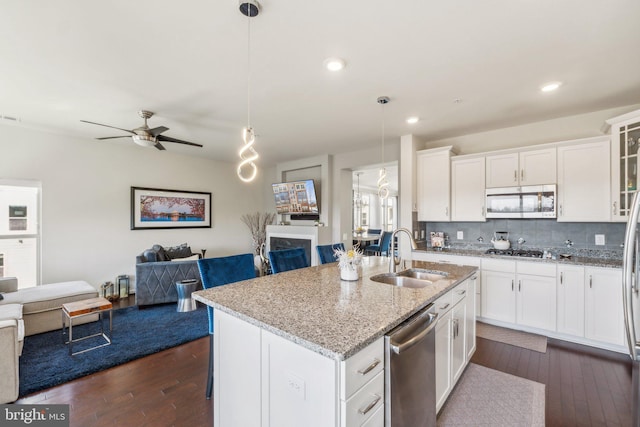 kitchen with open floor plan, backsplash, appliances with stainless steel finishes, and a sink