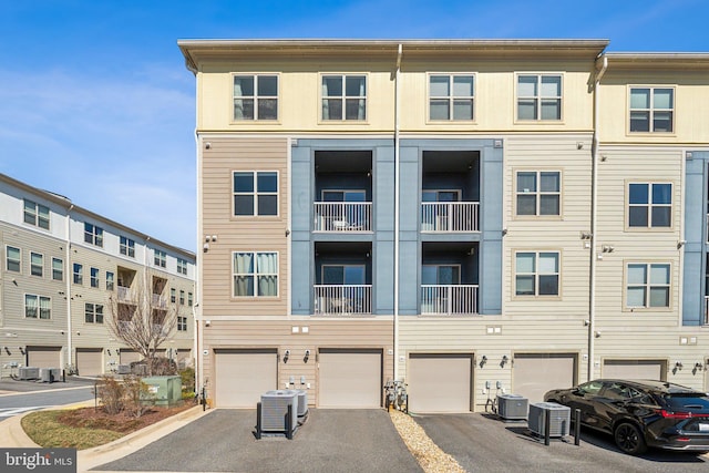 view of building exterior featuring driveway, an attached garage, and central AC