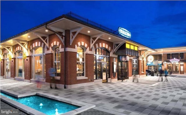 exterior space featuring brick siding, a patio area, and an outdoor pool