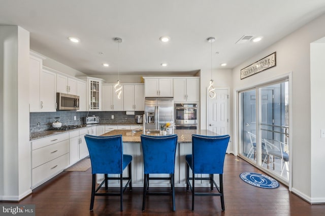 kitchen featuring tasteful backsplash, glass insert cabinets, dark wood-style floors, white cabinets, and stainless steel appliances