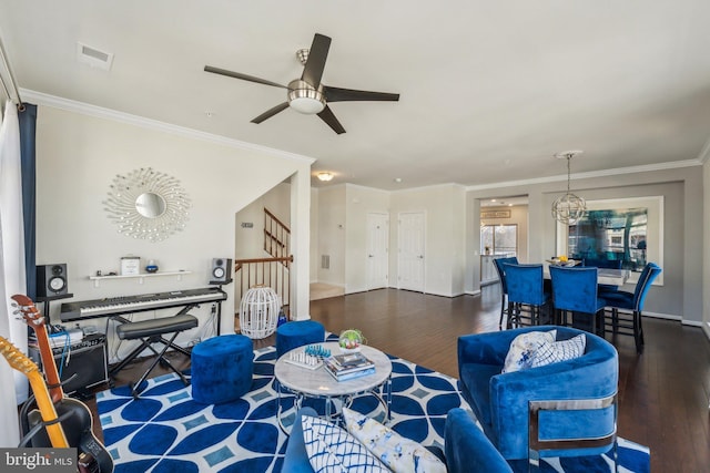 living area featuring visible vents, crown molding, ceiling fan, stairway, and wood finished floors