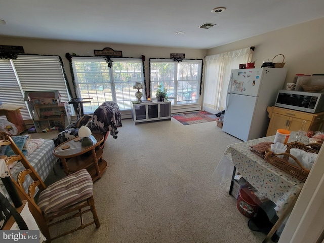 living area with visible vents and a baseboard heating unit