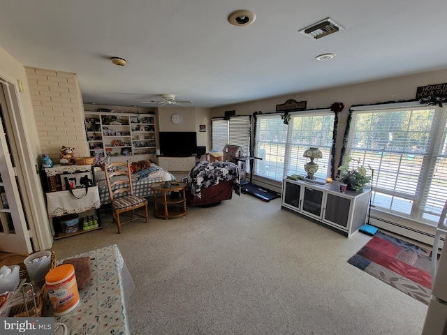 living area featuring visible vents, a healthy amount of sunlight, a baseboard heating unit, and a ceiling fan