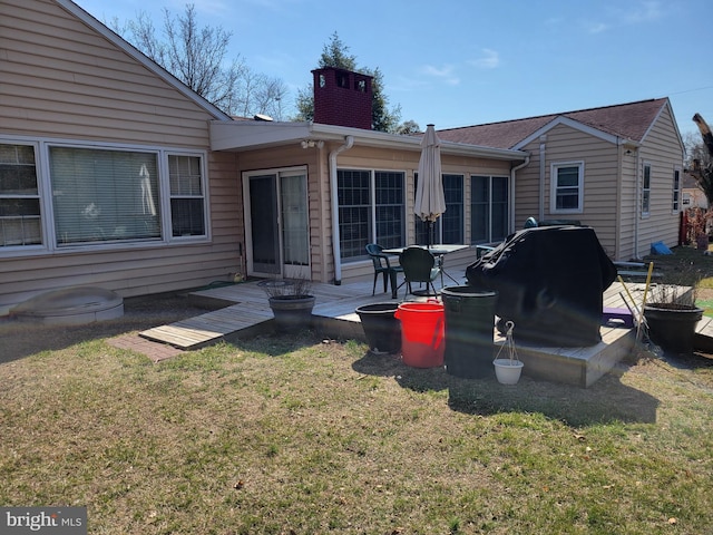 back of property featuring a chimney and a yard