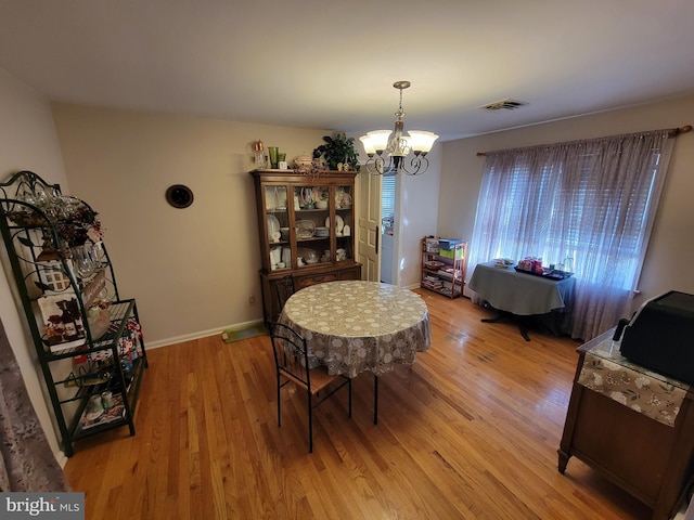 dining area with light wood-type flooring, visible vents, baseboards, and a chandelier