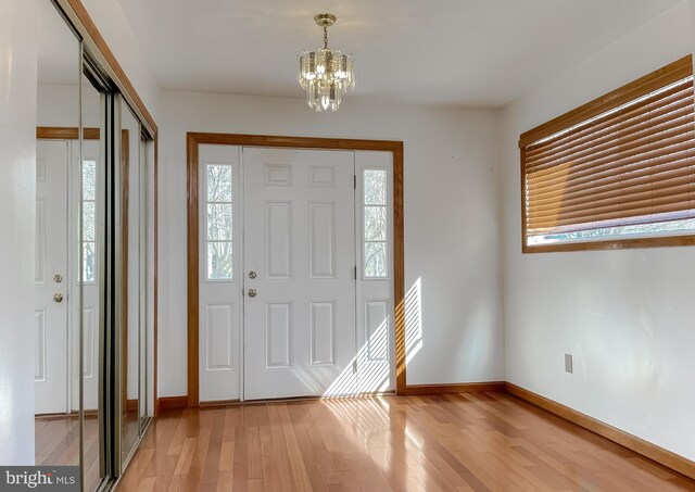 foyer featuring a chandelier, baseboards, and light wood-style flooring