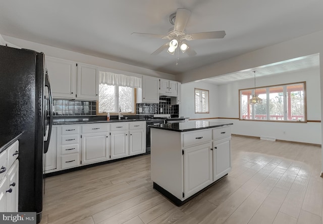 kitchen with visible vents, light wood finished floors, freestanding refrigerator, tasteful backsplash, and a center island