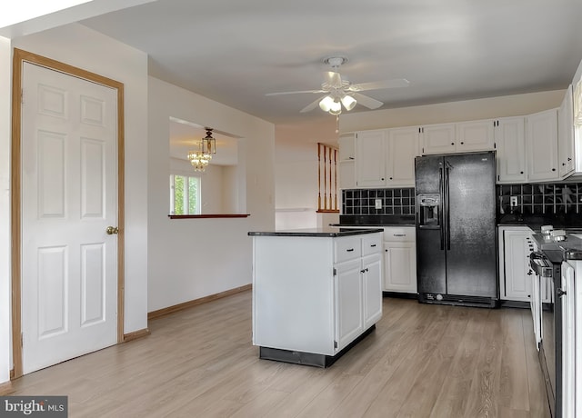 kitchen with light wood-type flooring, electric range, black fridge, dark countertops, and white cabinetry