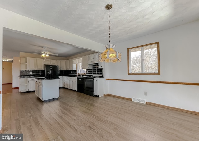 kitchen with dark countertops, a healthy amount of sunlight, black appliances, and wood finished floors