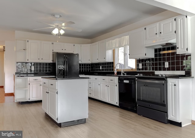 kitchen with black appliances, under cabinet range hood, a sink, dark countertops, and a center island