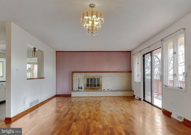 unfurnished living room with visible vents, baseboards, wood finished floors, and a fireplace