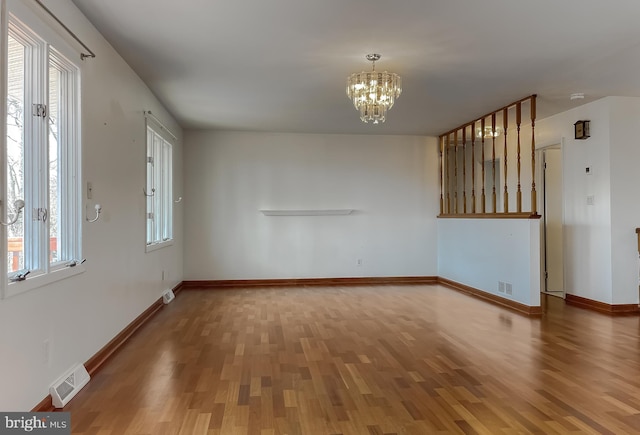 interior space featuring visible vents, baseboards, an inviting chandelier, and wood finished floors