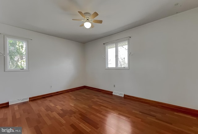 spare room with wood finished floors, visible vents, and baseboards