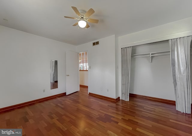 unfurnished bedroom featuring wood finished floors, visible vents, baseboards, ceiling fan, and a closet