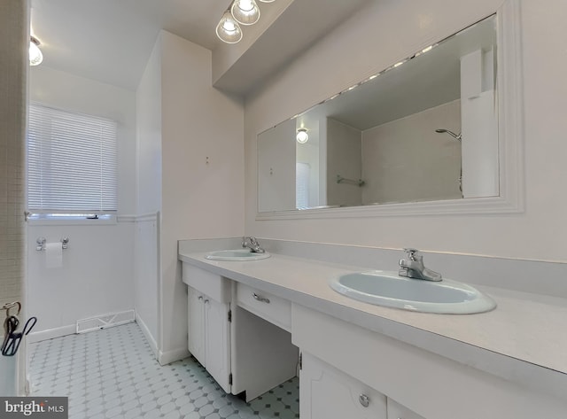 full bath with a sink, baseboards, walk in shower, and double vanity