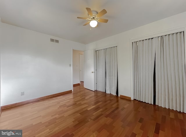 unfurnished bedroom featuring a ceiling fan, wood finished floors, visible vents, and baseboards