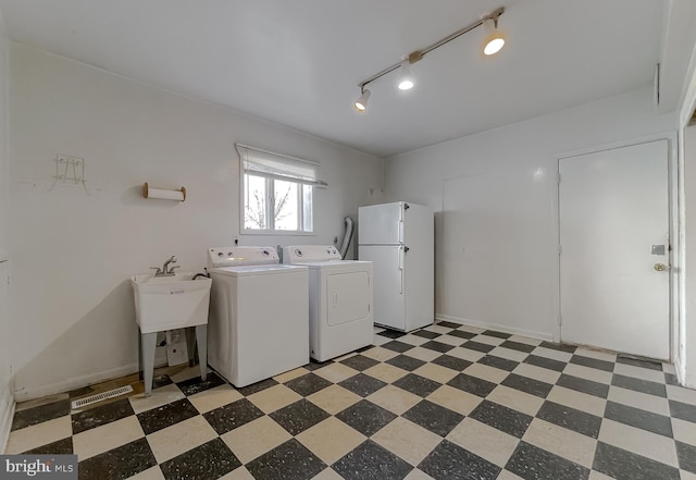 laundry area with washer and clothes dryer, light floors, baseboards, and a sink