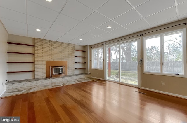 unfurnished living room with visible vents, built in features, baseboards, and wood finished floors