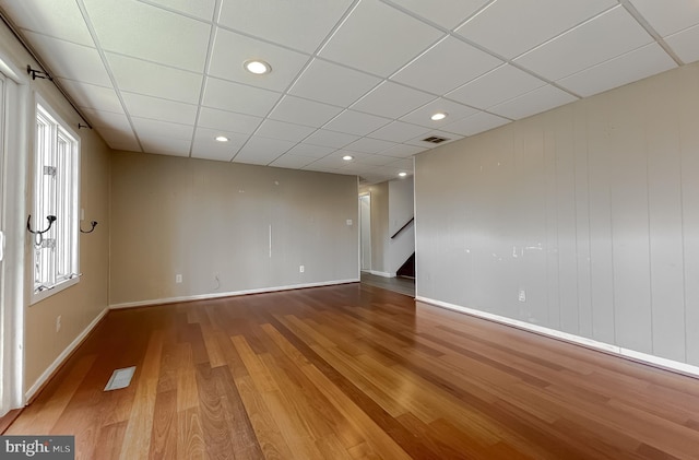 unfurnished room featuring visible vents, baseboards, wood finished floors, and stairs