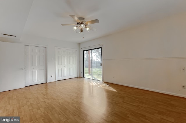 unfurnished bedroom featuring multiple closets, a ceiling fan, access to outside, light wood finished floors, and baseboards