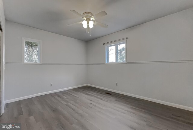 spare room featuring visible vents, ceiling fan, baseboards, and wood finished floors