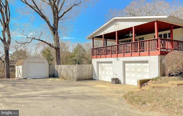 view of side of property featuring a storage unit, an outdoor structure, a ceiling fan, and fence