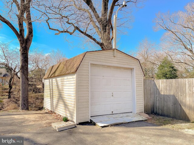 detached garage featuring fence and driveway