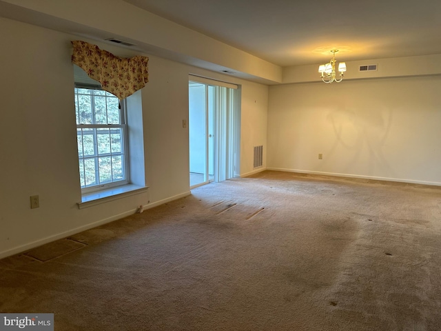 unfurnished room with a notable chandelier, visible vents, and carpet floors