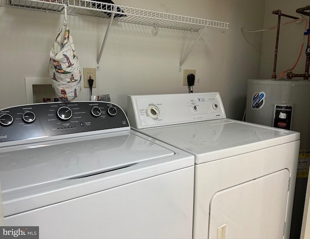 washroom with electric water heater, washing machine and dryer, and laundry area