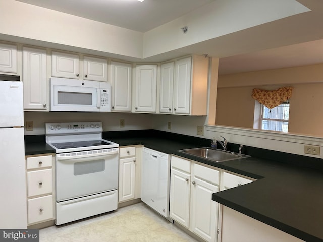 kitchen with white appliances, white cabinets, dark countertops, and a sink