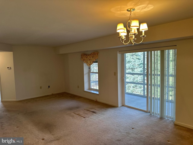 empty room featuring baseboards, carpet floors, and a notable chandelier