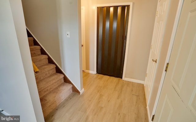 foyer featuring stairway, baseboards, and light wood finished floors