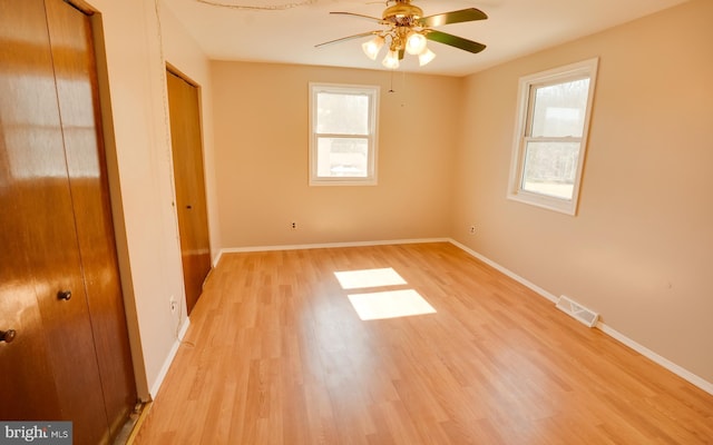 unfurnished bedroom with light wood finished floors, visible vents, multiple windows, and multiple closets